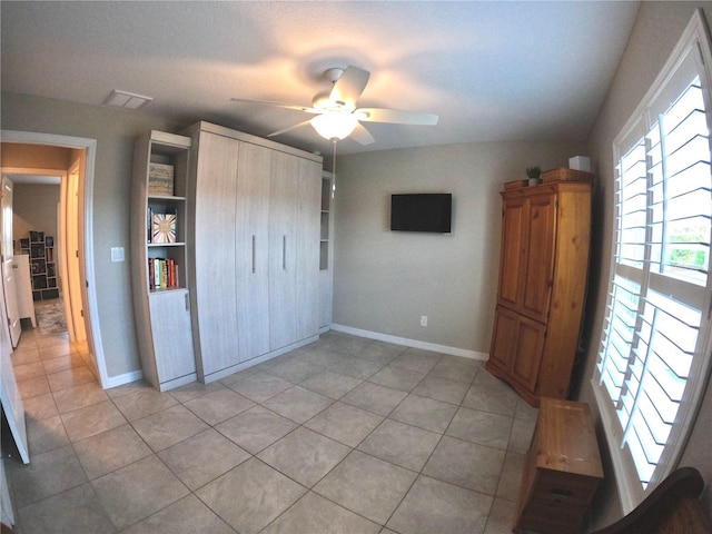 unfurnished bedroom with a ceiling fan, a closet, baseboards, and light tile patterned floors