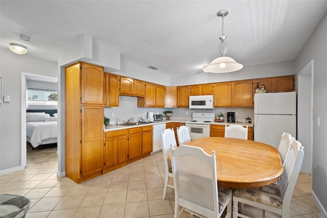 kitchen with white appliances, a sink, light countertops, brown cabinetry, and decorative light fixtures