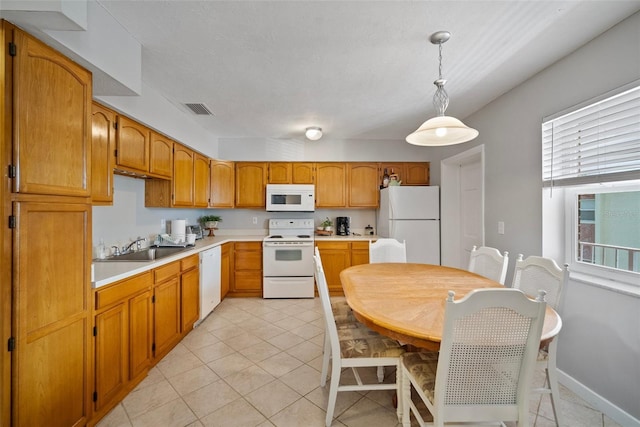 kitchen with white appliances, a sink, visible vents, hanging light fixtures, and light countertops