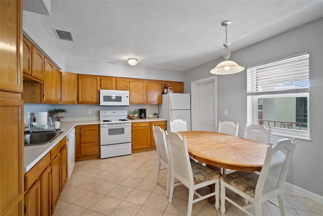 kitchen featuring light countertops, hanging light fixtures, visible vents, a sink, and white appliances