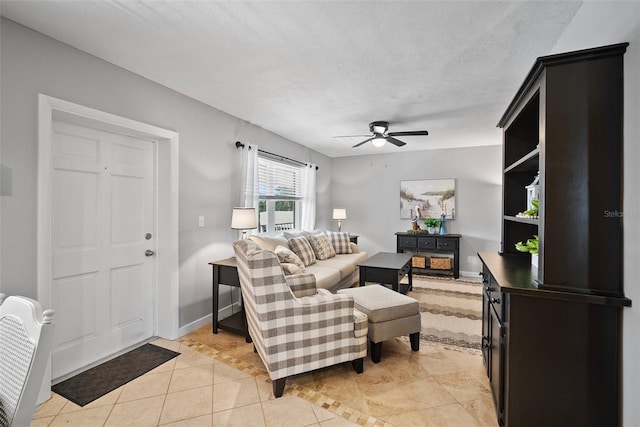 living area with a ceiling fan, light tile patterned flooring, a textured ceiling, and baseboards