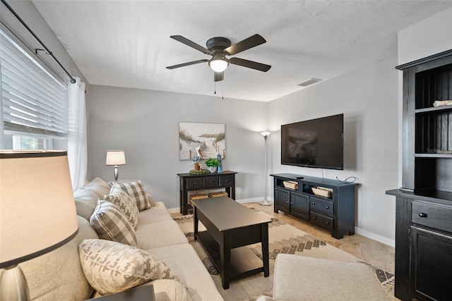 living room featuring a ceiling fan, visible vents, a textured ceiling, and baseboards