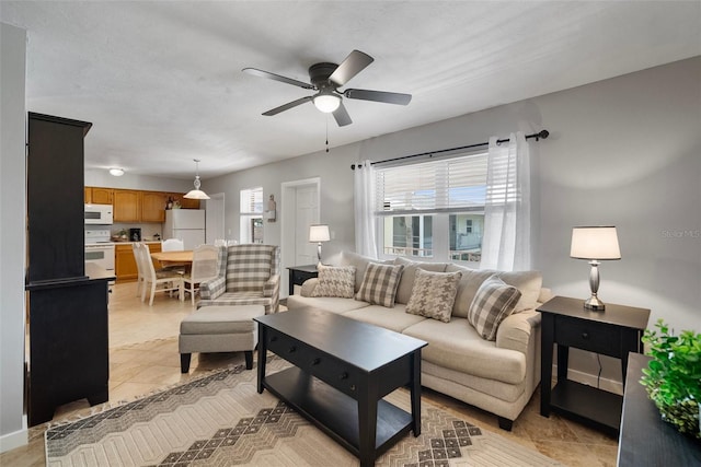 living area featuring light tile patterned flooring, a ceiling fan, and baseboards