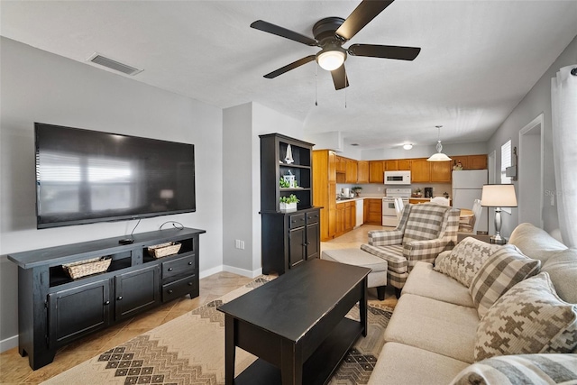 living room featuring a ceiling fan, visible vents, baseboards, and light tile patterned floors