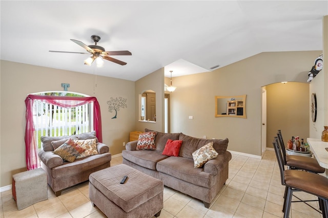 living area with arched walkways, light tile patterned flooring, a ceiling fan, and vaulted ceiling