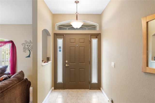 entrance foyer featuring light tile patterned floors, baseboards, and arched walkways