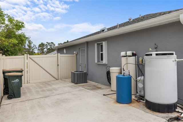 view of side of home with fence, stucco siding, cooling unit, a patio, and a gate