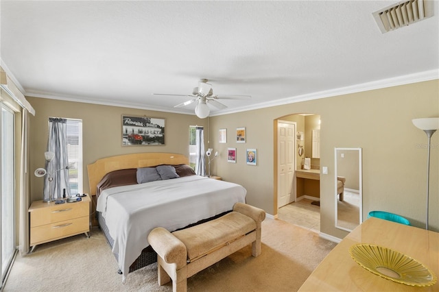 bedroom with visible vents, arched walkways, ceiling fan, ornamental molding, and light colored carpet