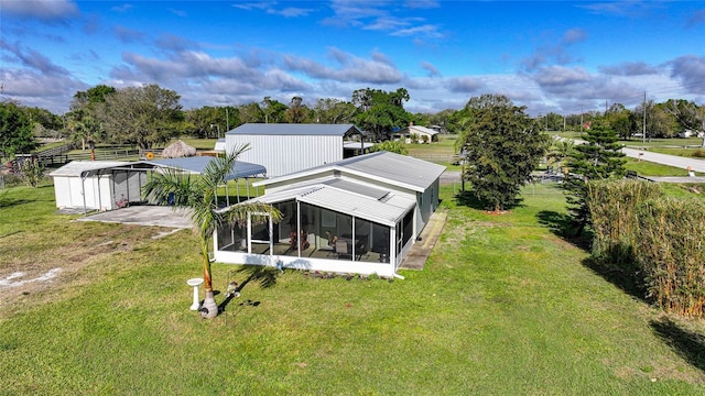 rear view of house featuring metal roof, a yard, and a sunroom