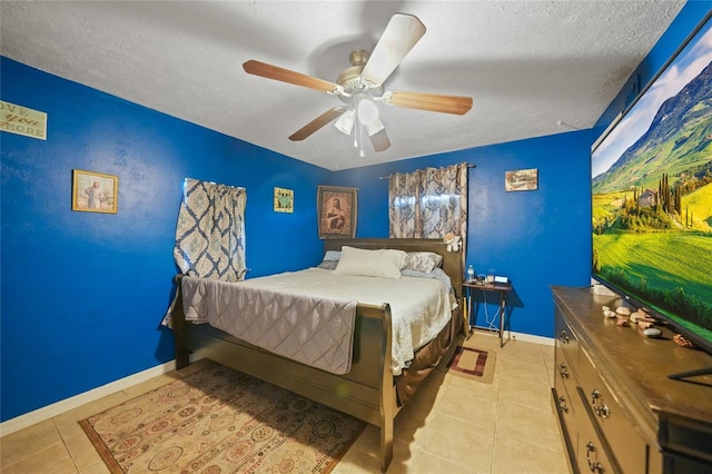bedroom with light tile patterned floors, a textured ceiling, a ceiling fan, and baseboards