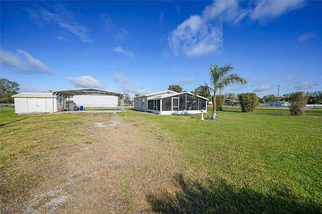 view of yard with a sunroom, fence, and a detached carport