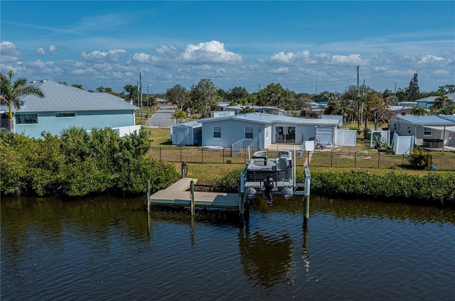 dock area with a water view, a fenced backyard, and a yard