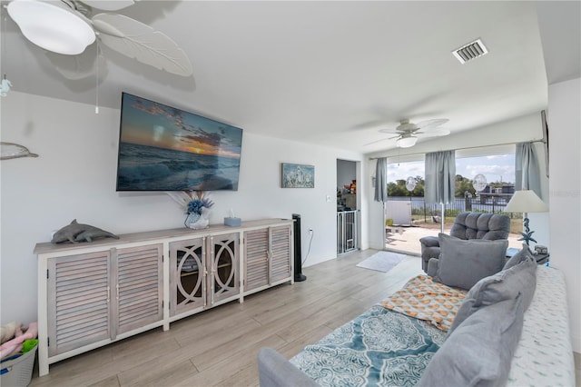 living room featuring visible vents, wood finished floors, and a ceiling fan