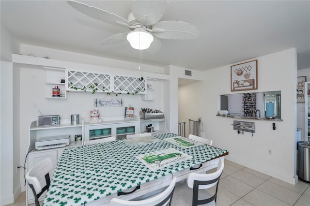 dining room featuring light tile patterned floors, baseboards, visible vents, a ceiling fan, and a bar