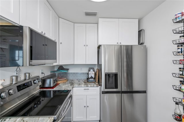 kitchen with appliances with stainless steel finishes, light stone countertops, visible vents, and white cabinetry