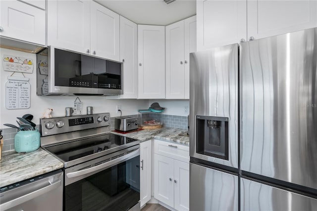 kitchen with light stone countertops, appliances with stainless steel finishes, and white cabinets