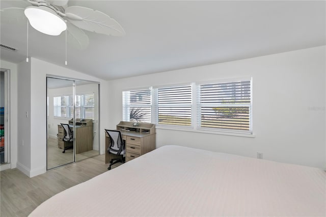 bedroom with a closet, visible vents, light wood-style flooring, a ceiling fan, and vaulted ceiling