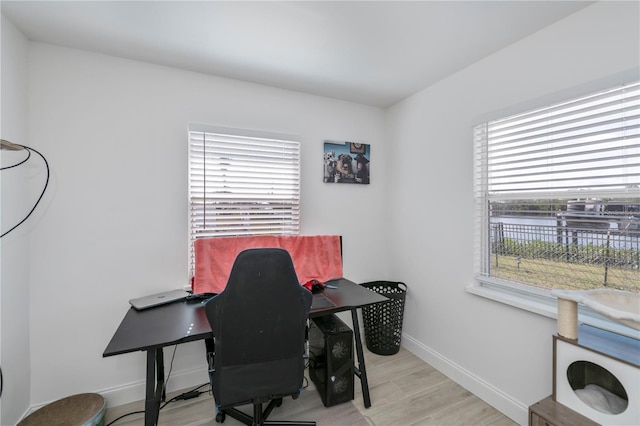 office with a water view, baseboards, and wood finished floors