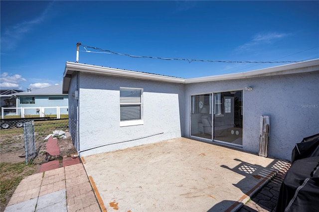 rear view of property with a patio, fence, and stucco siding