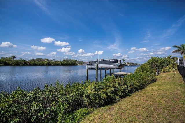 view of dock with a water view, a lawn, and boat lift