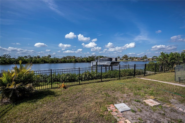 view of yard featuring a water view, boat lift, fence, and a boat dock