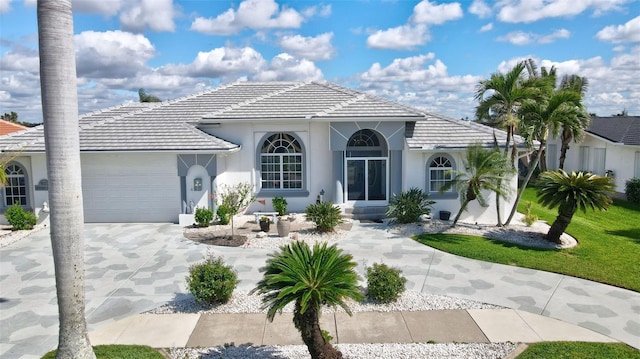 mediterranean / spanish house with concrete driveway, a tiled roof, an attached garage, and stucco siding