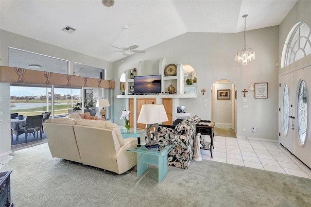 living room featuring visible vents, arched walkways, light colored carpet, ceiling fan with notable chandelier, and light tile patterned flooring