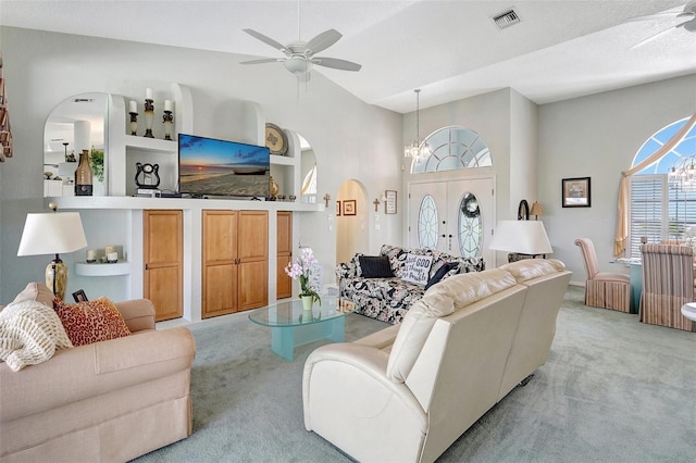 living room featuring light carpet, ceiling fan with notable chandelier, visible vents, and built in features