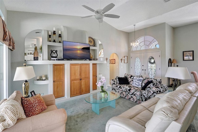 living area featuring built in shelves, arched walkways, light colored carpet, vaulted ceiling, and a textured ceiling