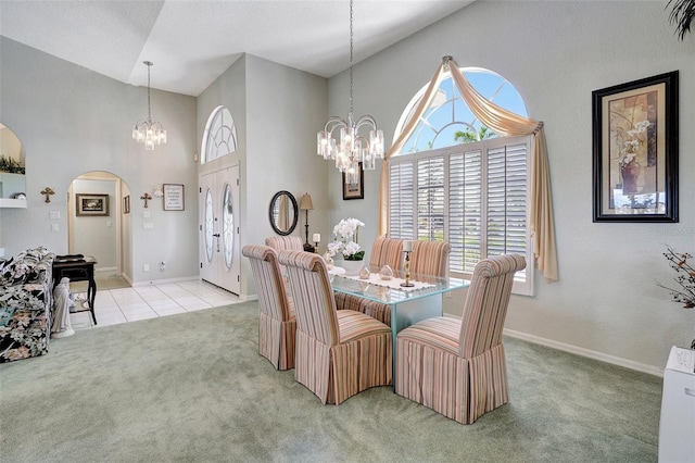 dining room with a chandelier, light carpet, and arched walkways