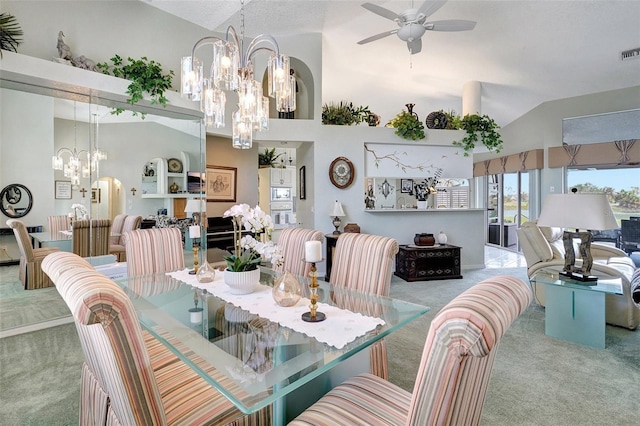 carpeted dining room featuring high vaulted ceiling, visible vents, and ceiling fan with notable chandelier