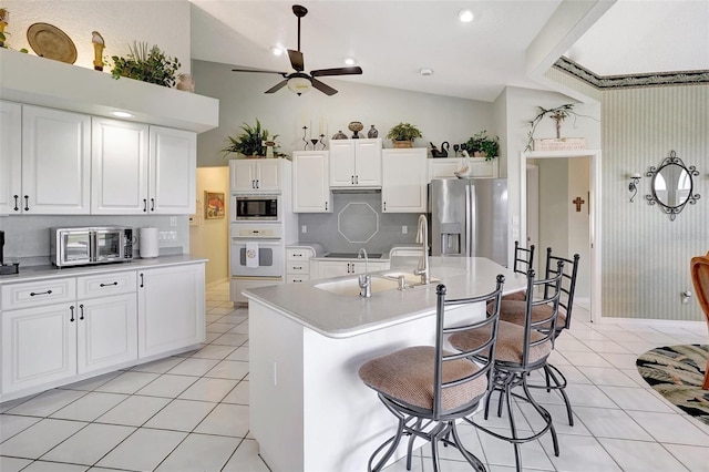 kitchen with stainless steel appliances, light countertops, a kitchen island with sink, white cabinetry, and light tile patterned flooring