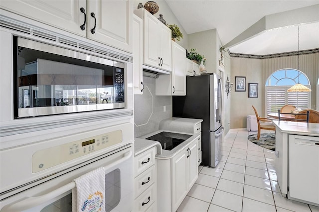 kitchen with light tile patterned floors, stainless steel appliances, lofted ceiling, light countertops, and white cabinetry