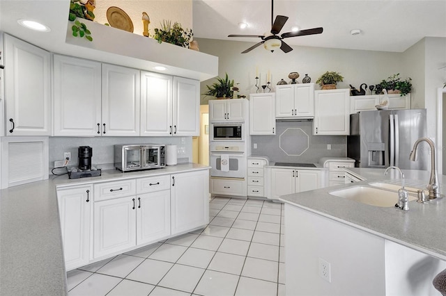 kitchen with stainless steel appliances, light countertops, white cabinetry, and a sink