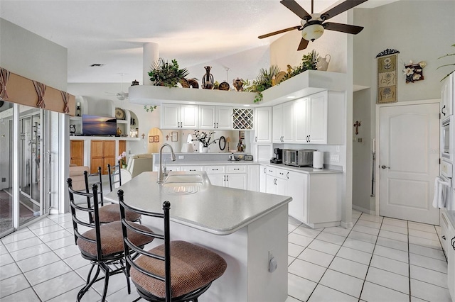 kitchen featuring light countertops, an island with sink, a sink, and white cabinets