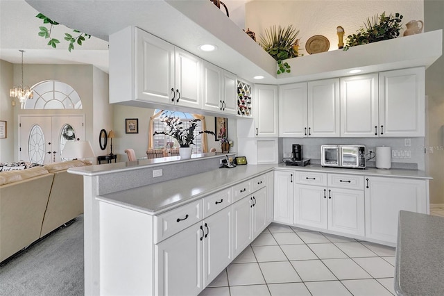 kitchen with a peninsula, white cabinetry, open floor plan, light countertops, and pendant lighting