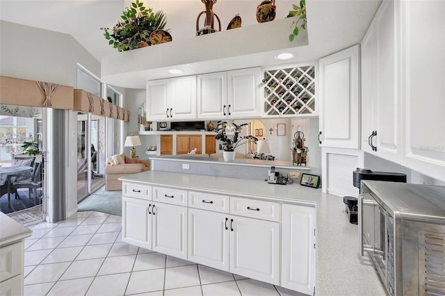 kitchen with lofted ceiling, light countertops, stainless steel microwave, and white cabinets