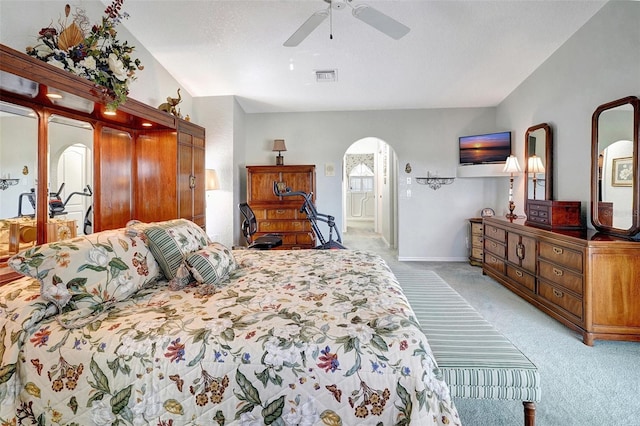 bedroom with visible vents, arched walkways, a ceiling fan, baseboards, and light colored carpet