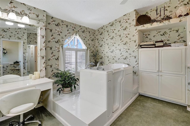 bathroom featuring a garden tub, a textured ceiling, vanity, and wallpapered walls