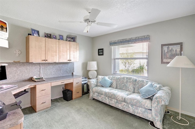 office space featuring a textured ceiling, built in study area, a ceiling fan, and light colored carpet