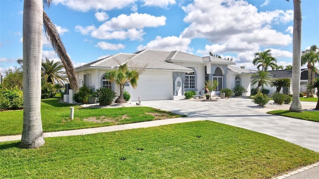 mediterranean / spanish-style house featuring stucco siding, an attached garage, a front yard, driveway, and a tiled roof