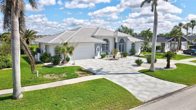 mediterranean / spanish-style home with concrete driveway, a tiled roof, an attached garage, a front yard, and stucco siding