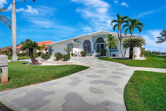 mediterranean / spanish-style home with a garage, a front yard, concrete driveway, and stucco siding