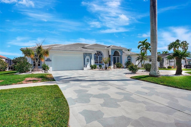 view of front facade with a garage, driveway, a front lawn, and stucco siding