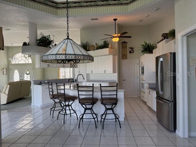 507 Monaco Dr, Punta Gorda, FL 33950 - kitchen featuring stainless steel appliances, a towering ceiling, a breakfast bar area, open floor plan, and white cabinets