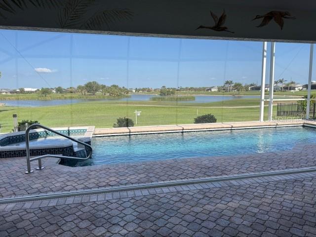 507 Monaco Dr, Punta Gorda, FL 33950 - view of pool with a water view, a ceiling fan, a pool with connected hot tub, and a lawn