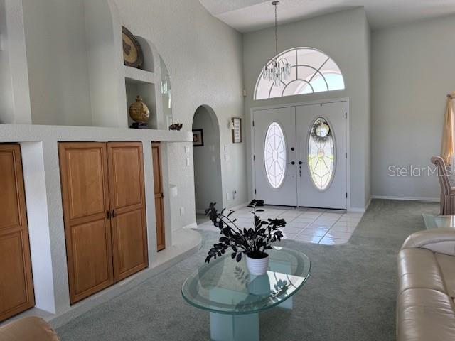 507 Monaco Dr, Punta Gorda, FL 33950 - foyer entrance featuring light carpet, a high ceiling, arched walkways, a chandelier, and light tile patterned floors
