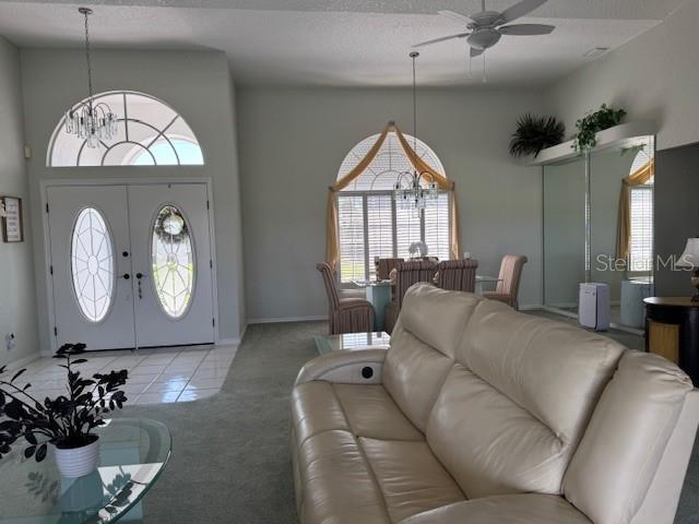 507 Monaco Dr, Punta Gorda, FL 33950 - living room featuring a ceiling fan, a chandelier, carpet floors, tile patterned flooring, and a towering ceiling