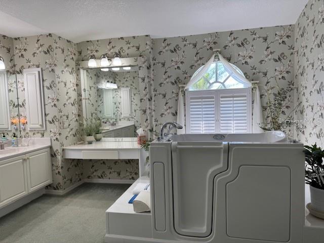 507 Monaco Dr, Punta Gorda, FL 33950 - full bath featuring wallpapered walls, a bath, two vanities, and baseboards