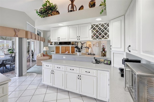 507 Monaco Dr, Punta Gorda, FL 33950 - kitchen with a peninsula, light countertops, white cabinets, vaulted ceiling, and light tile patterned floors